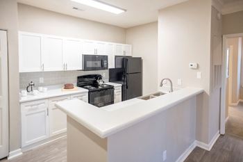 Spacious kitchen with white cabinetry and black appliances  